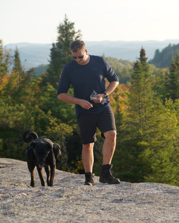 Homme en randonnée de montagne avec son chien équipé du harnais Odyssé Onyx et du sac à dos Odyssé noir Amarok, idéal pour les activités plein air.